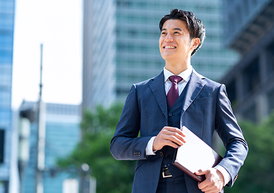 税理士紹介サービスのイメージ - プロフェッショナルな男性がオフィスビル前で書類を持って立っている様子